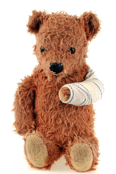 Teddybär mit bandagiertem Arm in Großaufnahme auf weißem Hintergrund - Foto, Bild