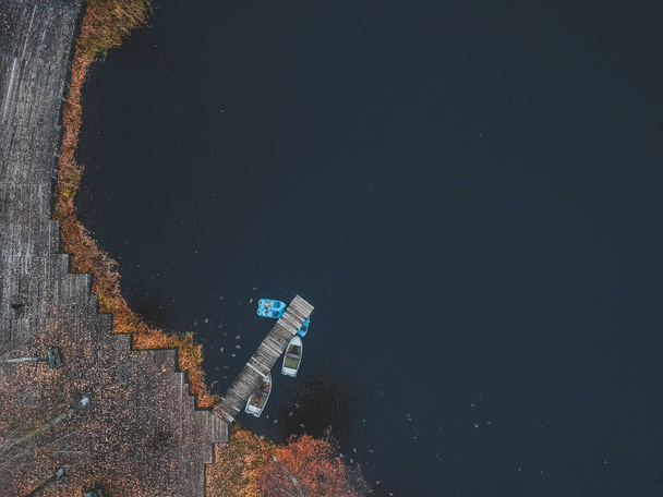Muelle de vista aérea con botes de madera en la orilla de un lago pintoresco, bosque de otoño. San Petersburgo, Rusia
. - Foto, imagen