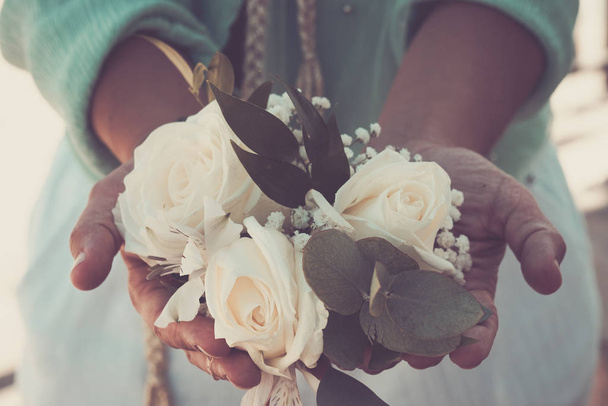 Klasik soğuk mavi renkler. Kadın elleri beyaz romantik güller alıyor. - Fotoğraf, Görsel