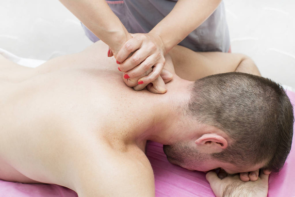 The procedure for sports massage for an athlete is done by a woman in a massage parlor. - Fotoğraf, Görsel