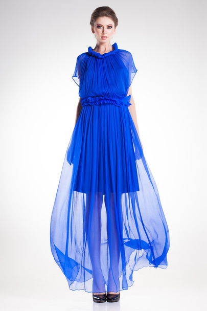 Hermosa modelo de mujer posando en vestido largo y elegante de seda azul en el estudio
 - Foto, imagen