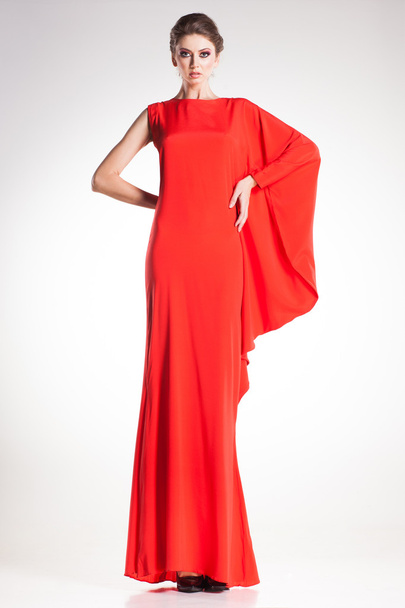 krásná žena model představuje v jednoduché elegantní červených šatech v ateliéru - Fotografie, Obrázek