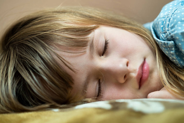 Portret ślicznej dziewczynki śpiącej w łóżku. - Zdjęcie, obraz