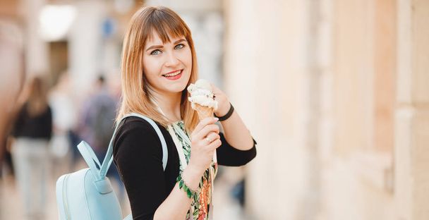 Gyönyörű lány turista tartja és eszik olasz fagylaltot kúp és belenéz keret - Fotó, kép