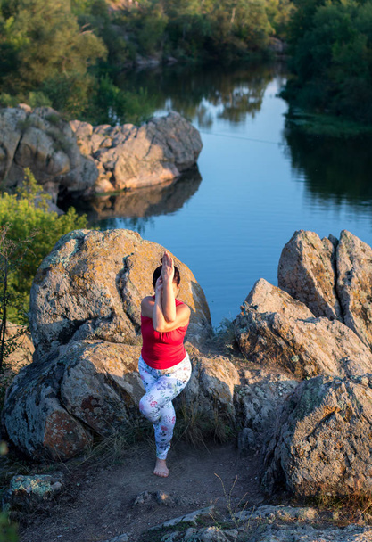 mulher adulta fazendo asanas ioga nas rochas acima do rio
 - Foto, Imagem