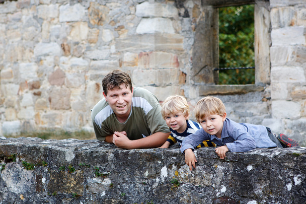 Jeune homme et ses deux petits garçons debout derrière le mur de vieux Ge
 - Photo, image