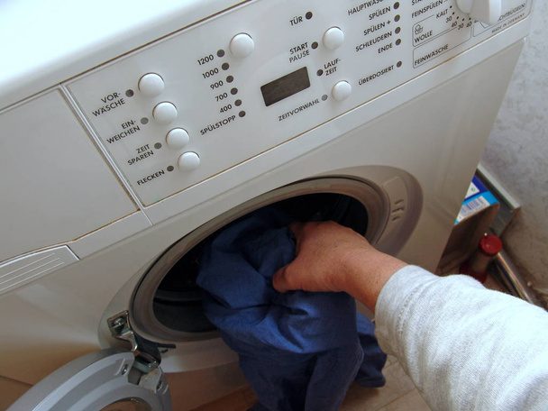 close up of female putting clothes in washing machine  - Photo, image