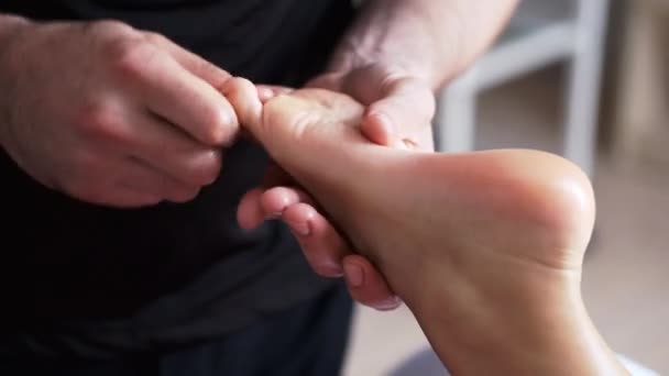 Masér dělá masáž nohou dospělé ženě v lázních - Záběry, video