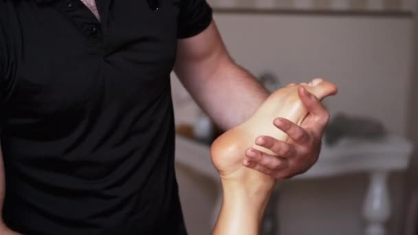 Masér dělá masáž nohou dospělé ženě v lázních - Záběry, video