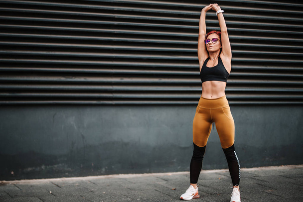 Portré fitt és sportos szexi nő csinál stretching a városi városi táj. Sport- és fitneszkoncepció - Fotó, kép