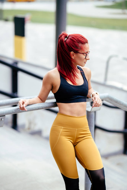 スポーツウェアに身を包んだセクシーな赤毛のアスレチック女性の肖像。集中的なフィットネストレーニングとトレーニング - 写真・画像