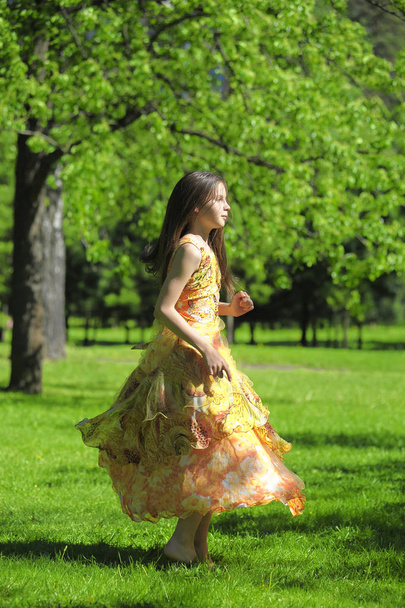 girl in an orange dress is spinning, runs in the summer in the p - Φωτογραφία, εικόνα