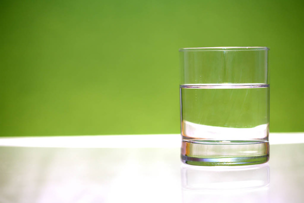 glass of water on a green background - Foto, Imagem