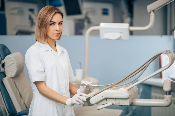 serious dentist woman using medical equipment at work - Foto, Imagen