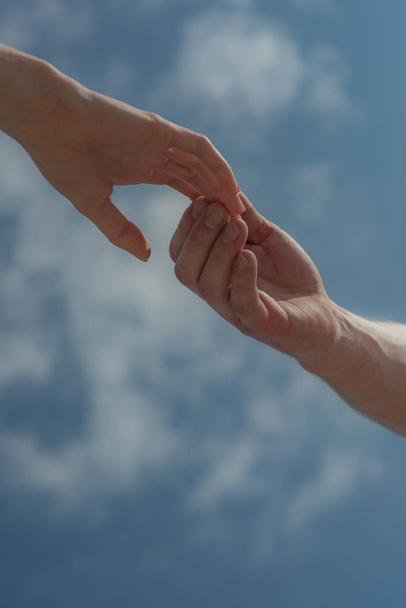 Hands on sky background. Mutual assistance. Couple. Love and mutual understanding. Two hands together. - Photo, Image