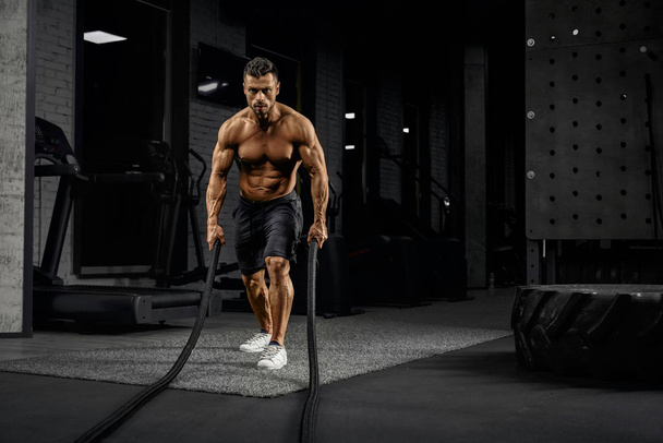 Muscular caucasian man training with ropes. - Zdjęcie, obraz