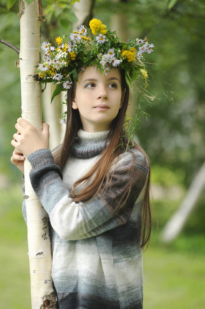 girl with a wreath of wild flowers on her head near a birch - Φωτογραφία, εικόνα