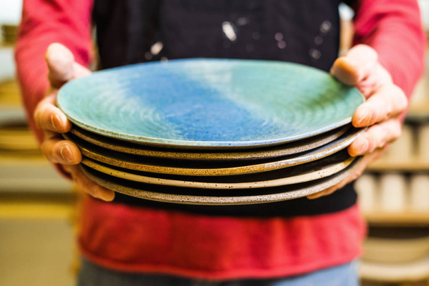Potter in studio holding hand made plates, hands detail, shallow debt of field, small art business concept - Photo, Image