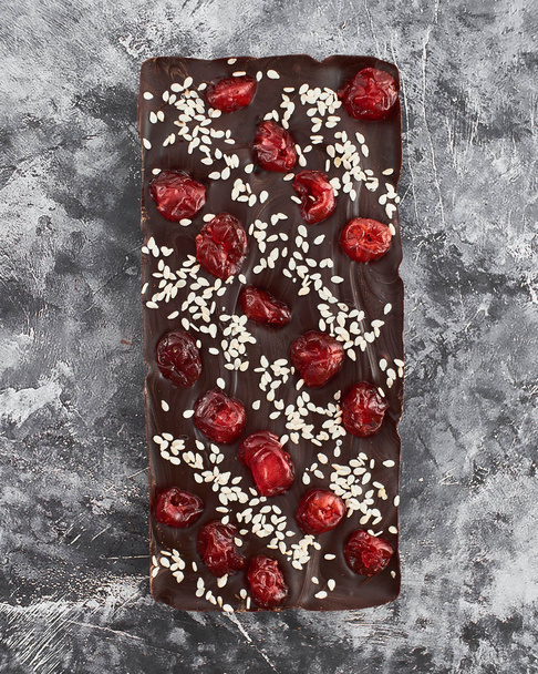 Handmade chocolate bar with cherry and sesame filling. - Фото, изображение