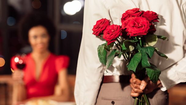 Felismerhetetlen férfi gazdaság rózsák miután dátum barátnő étteremben - Fotó, kép