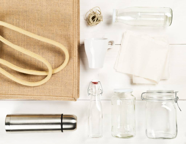 Zero waste or waste free shopping utensils with burlap bag, glass bottles and cotton bag on white wooden table background - Fotoğraf, Görsel