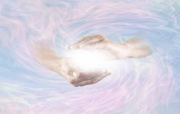 Werken met Krachtige Goddelijke Energie - mannelijke handen die tevoorschijn komen uit blauwe roze roterende energie veld achtergrond met helder wit licht energie tussen de handen - Foto, afbeelding
