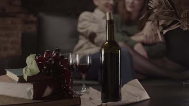 Bottle of wine and glasses and couple hugging on background, shallow depth of field - Záběry, video
