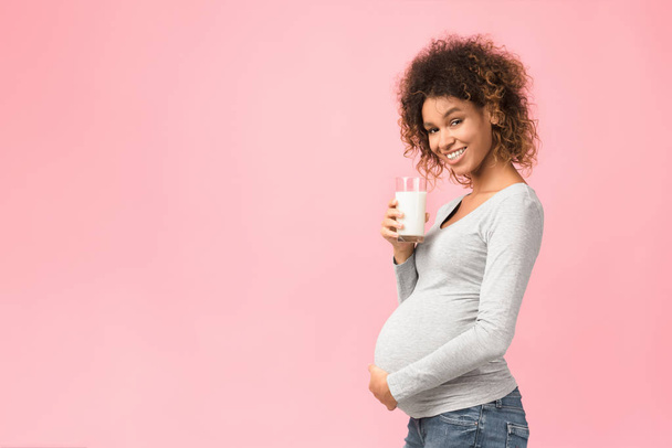 Afro raskaana oleva nainen tilalla lasi maitoa, vapaa tila
 - Valokuva, kuva