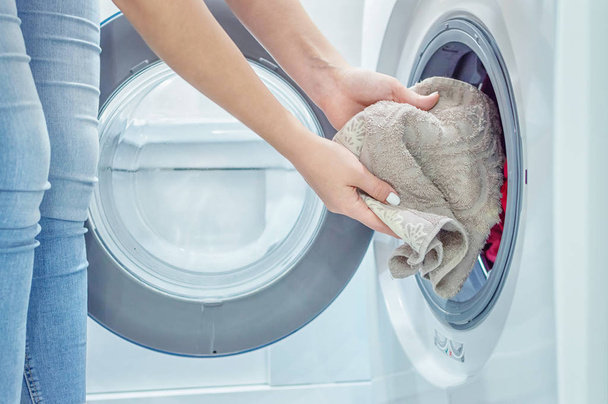 women's hands put Laundry in the washing machine. Housekeeper. Close up. Selective focus. Film grain - Foto, Bild