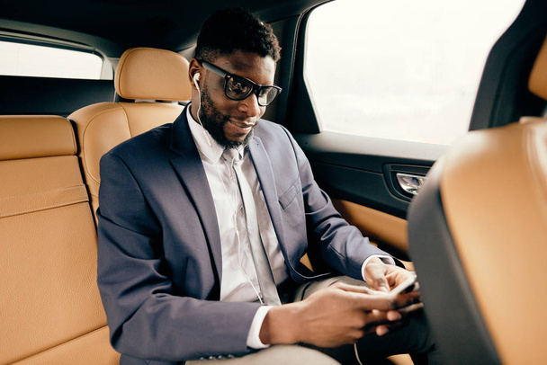 Homme d'affaires en costume assis dans un siège arrière de voiture à l'aide de son téléphone
. - Photo, image