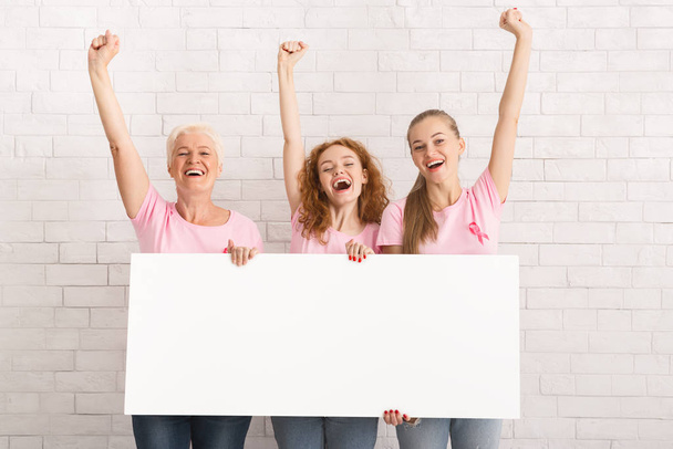Three Women In Pink T-Shirts Holding Poster Over White Wall - Photo, image