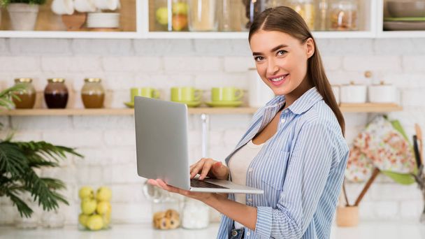 Searching for recipe. Girl using laptop in the kitchen - Foto, Bild