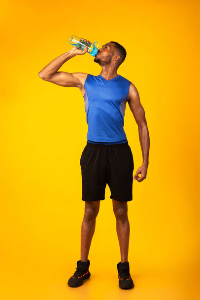 Healthy black sportsman drinking water from bottle - Photo, Image