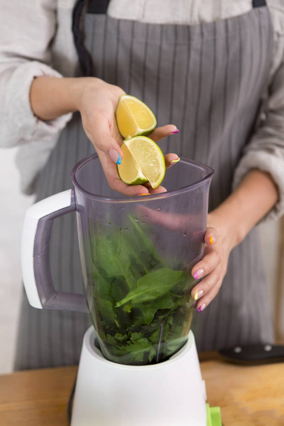 Unrecognizable woman with blender cup cooking healthy smoothie at home - Photo, image