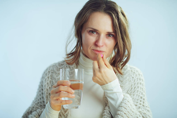 enferma ama de casa moderna con taza de agua que come píldora
 - Foto, imagen