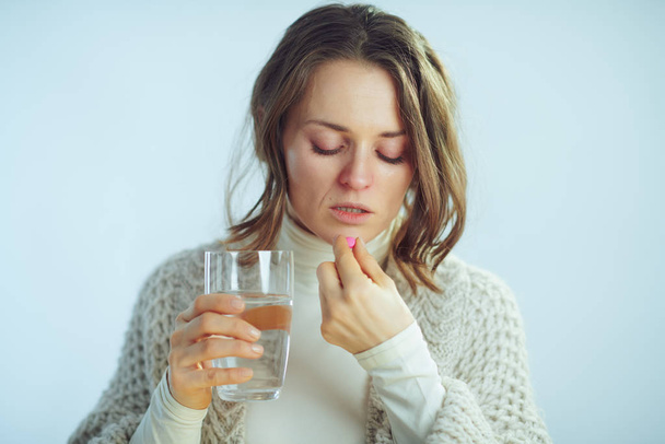 ill modern woman with cup of water eating pill - Photo, Image
