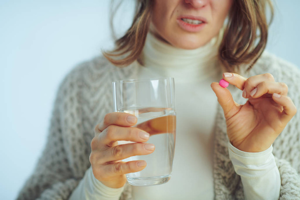 Closeup on tired sick elegant female with cup of water and pill - Фото, изображение