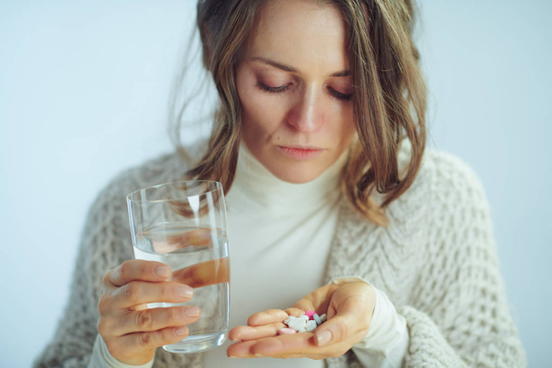 ενδιαφερόμενη γυναίκα με κύπελλο του νερού που κατέχουν διάφορα χάπια - Φωτογραφία, εικόνα
