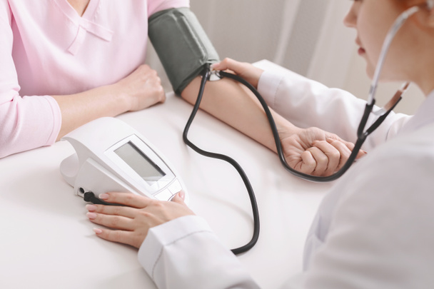 Doctor with tonometer checking blood pressure of woman - Foto, afbeelding