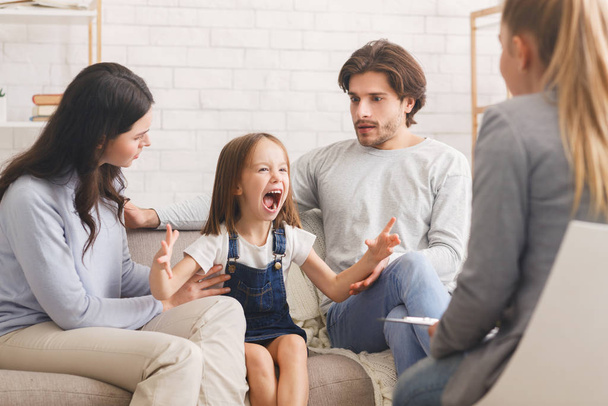 Schockierte Eltern beschwichtigen ihre schreiende kleine Tochter bei Psychologen-Sprechstunde - Foto, Bild