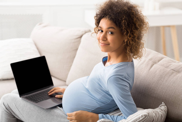 Afro mujer embarazada usando el ordenador portátil con pantalla en blanco - Foto, imagen