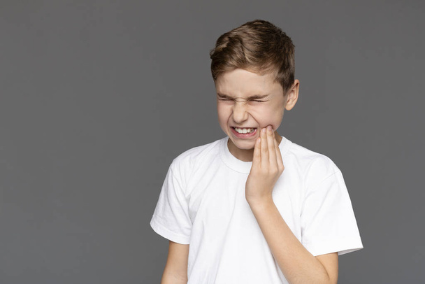 Teen chlapec s akutní bolestí zubů, šedé pozadí - Fotografie, Obrázek