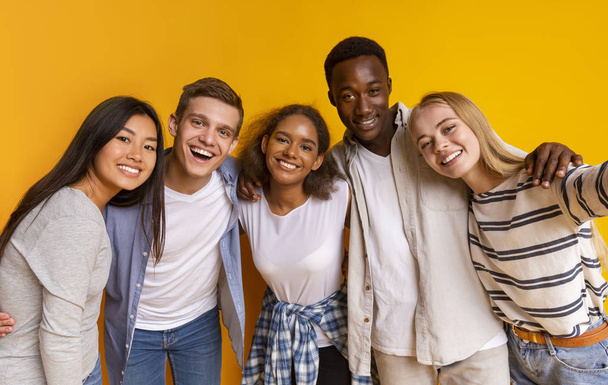 Amistosos estudiantes internacionales tomando selfie sobre fondo amarillo
 - Foto, imagen