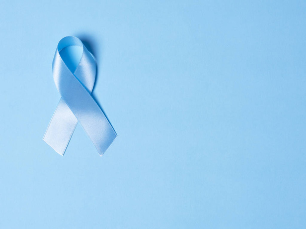 Μπλε σατέν κορδέλα σύμβολο της ευαισθητοποίησης του καρκίνου του προστάτη σε ένα φωτεινό μπλε φόντο. Έννοια της ιατρικής και της υγειονομικής περίθαλψης, αντίγραφο χώρο - Φωτογραφία, εικόνα