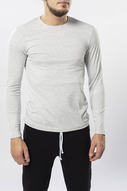sporty man in sweatpants and long sleeve t-shirt on white background, sports t-shirt close-u - Foto, imagen