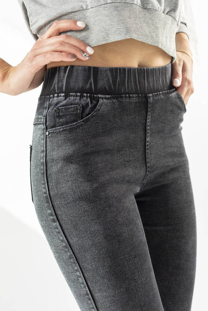 girl in jeans shows off jeans on a white background close-up, black jeans - Fotoğraf, Görsel