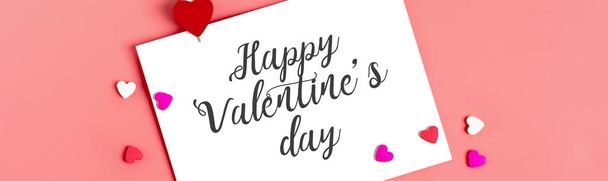 Egy fehér papírlap egy üzenethez egy szerettemnek, egy piros boríték és szív alakú cukorka rózsaszín háttérrel. Happy valentine day concept Flat lay Mock up Szöveg helye Felülnézet Banner - Fotó, kép