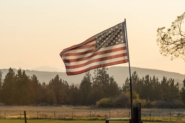 Coucher de soleil passe à travers un drapeau américain agitant près de Terrebonne
 - Photo, image