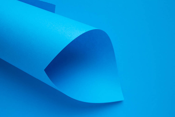 Rolled up roll of bright blue paper on a monochrome background close up with space for copying - Foto, immagini