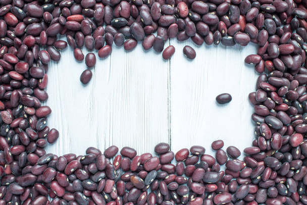 Rectangular frame of dry red beans spread out on a white wooden table with copy space - Foto, imagen
